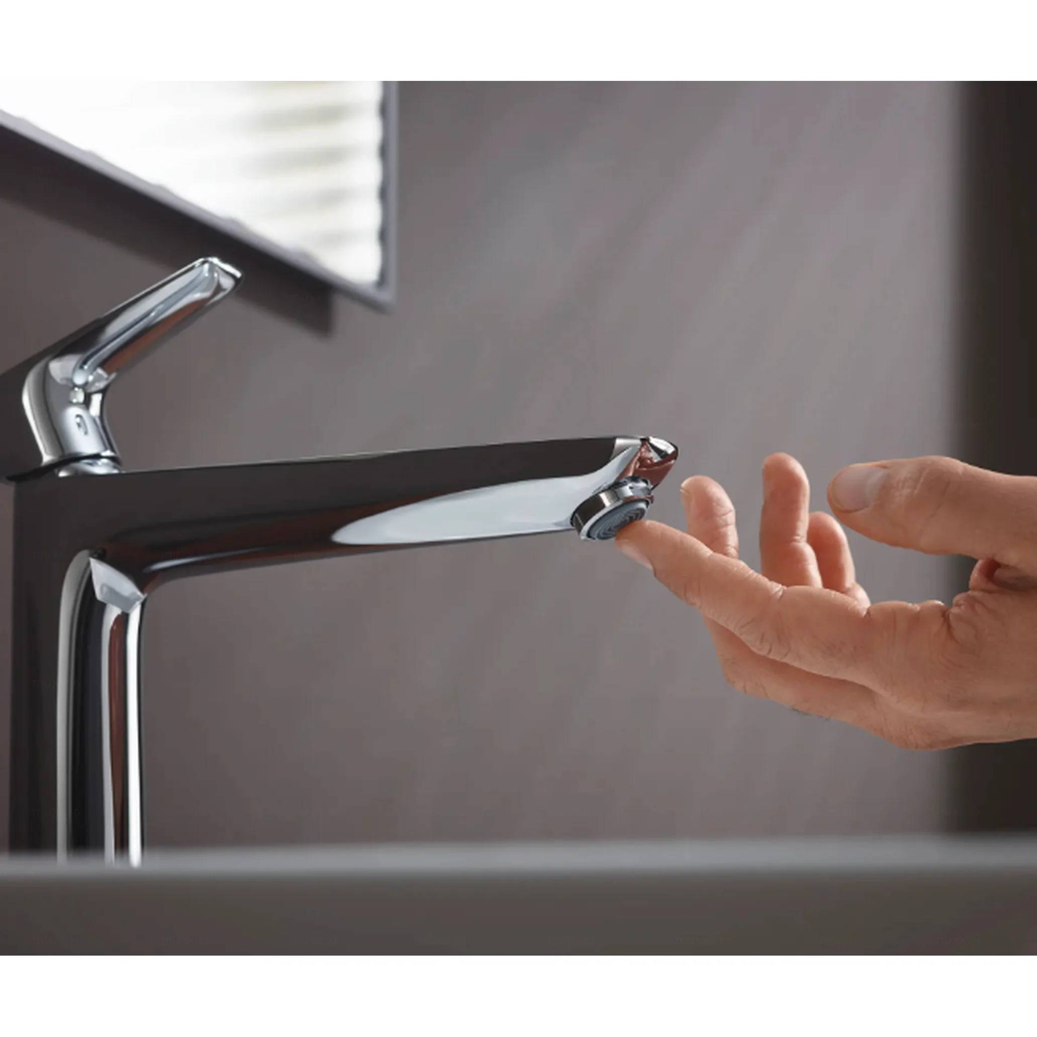 Hand reicht unter einen modernen Badezimmerhahn, als würde sie Wasser prüfen oder die Sensoraktivierung testen.