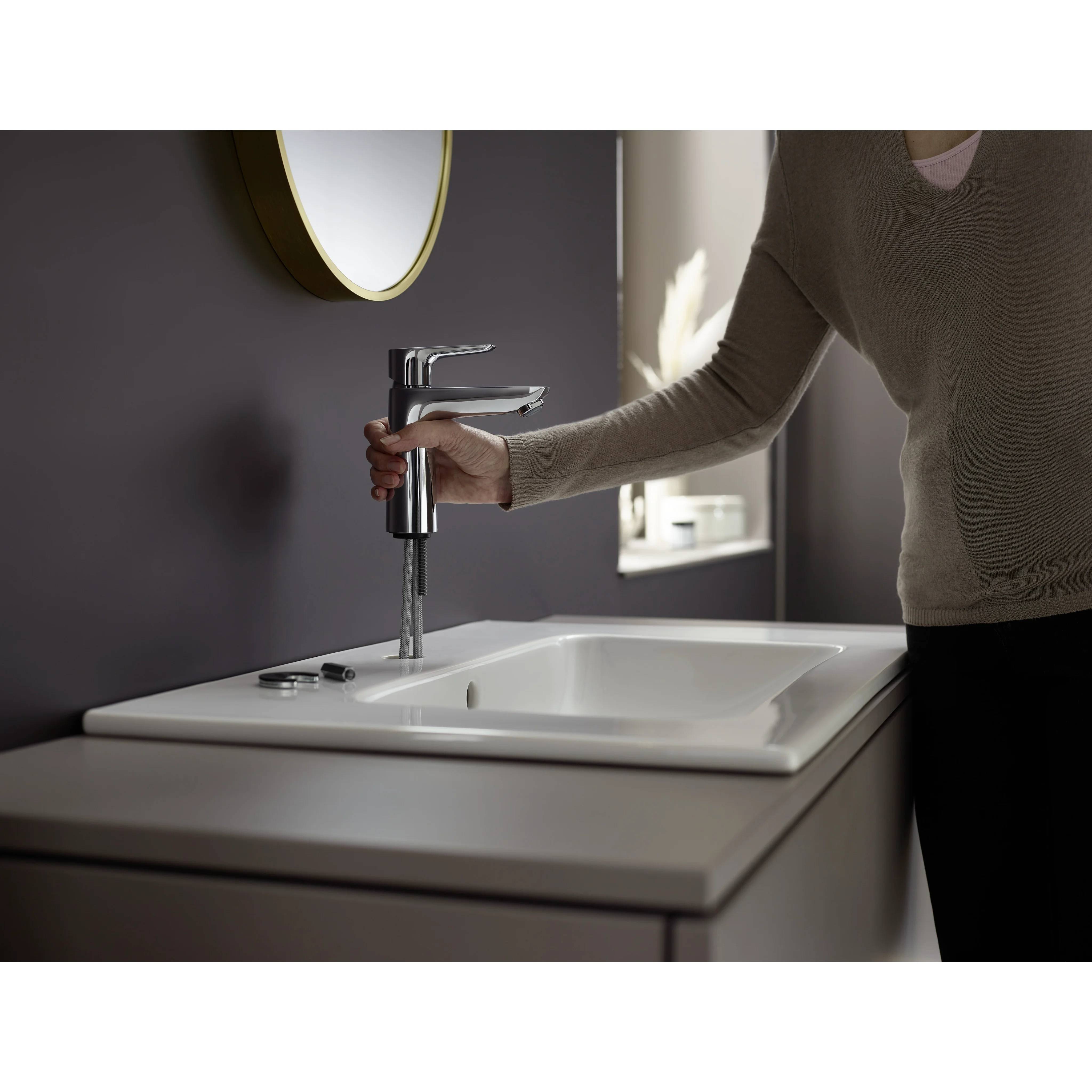 Person, die einen modernen Wasserhahn aus Chrom in ein weißes Waschbecken-Waschtisch einbaut.
