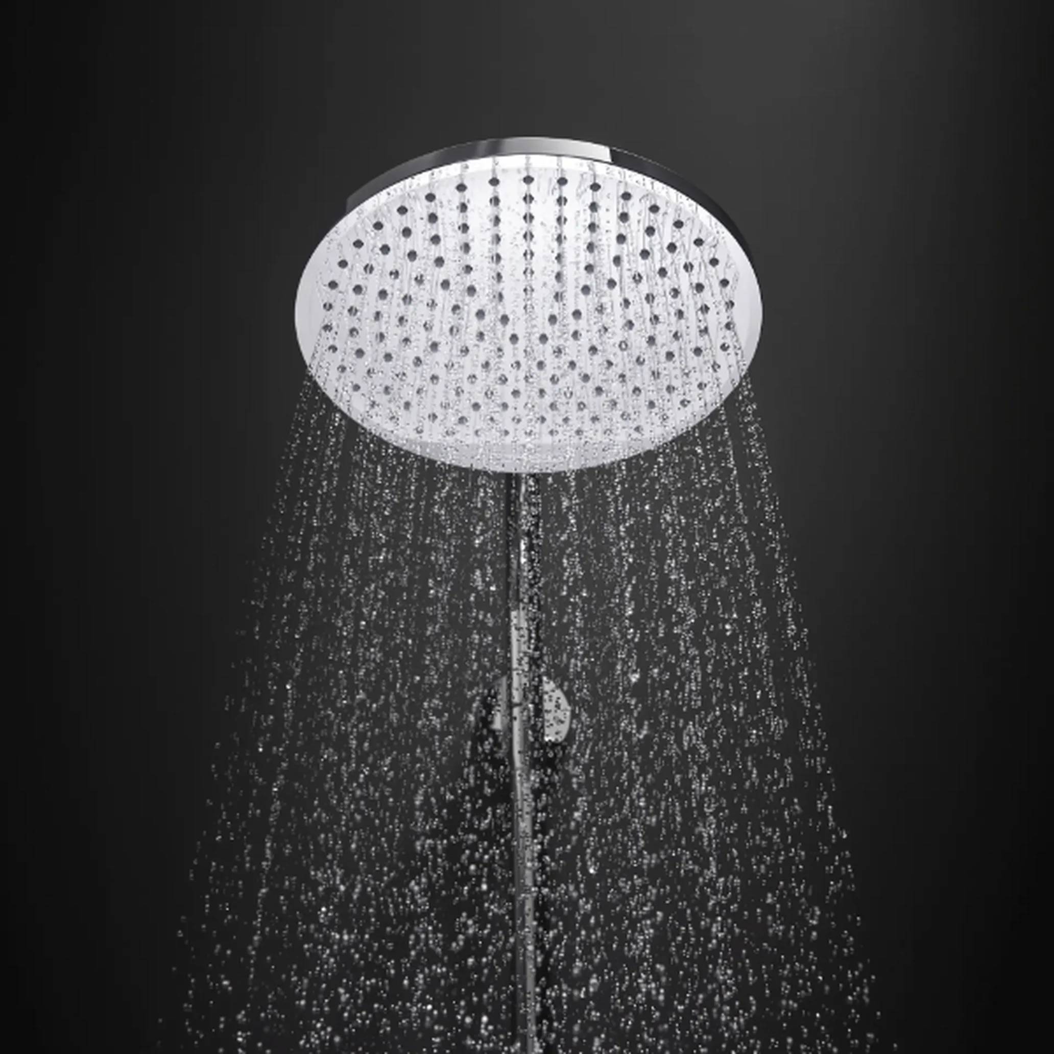 Ein runder Duschkopf zur Regenfallbewässerung sprüht Wasser nach unten in einer dunklen Badezimmerumgebung.