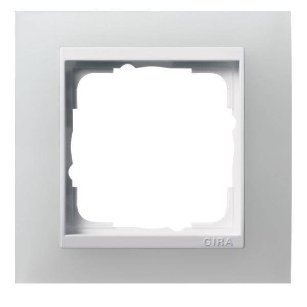 Ein quadratischer, silberner Rahmen für einen Lichtschalter mit einer zentralen weißen Öffnung, im unteren rechten Eck mit 'GIRA' beschriftet.