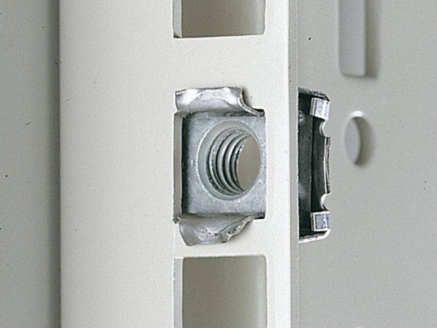 Detailaufnahme einer Metallmutter, die in eine hellfarben Platte mit quadratischen Ausschnitten eingesetzt wird, was eine Teile-Ausrichtungs- oder Montagetechnik veranschaulicht.