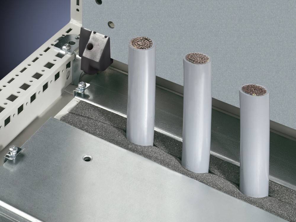 Drei vertikal ausgerichtete Kabel mit freigelegten Kupferdrähten sind auf einer Metallplatte montiert, umgeben von einer gepolsterten Basis.