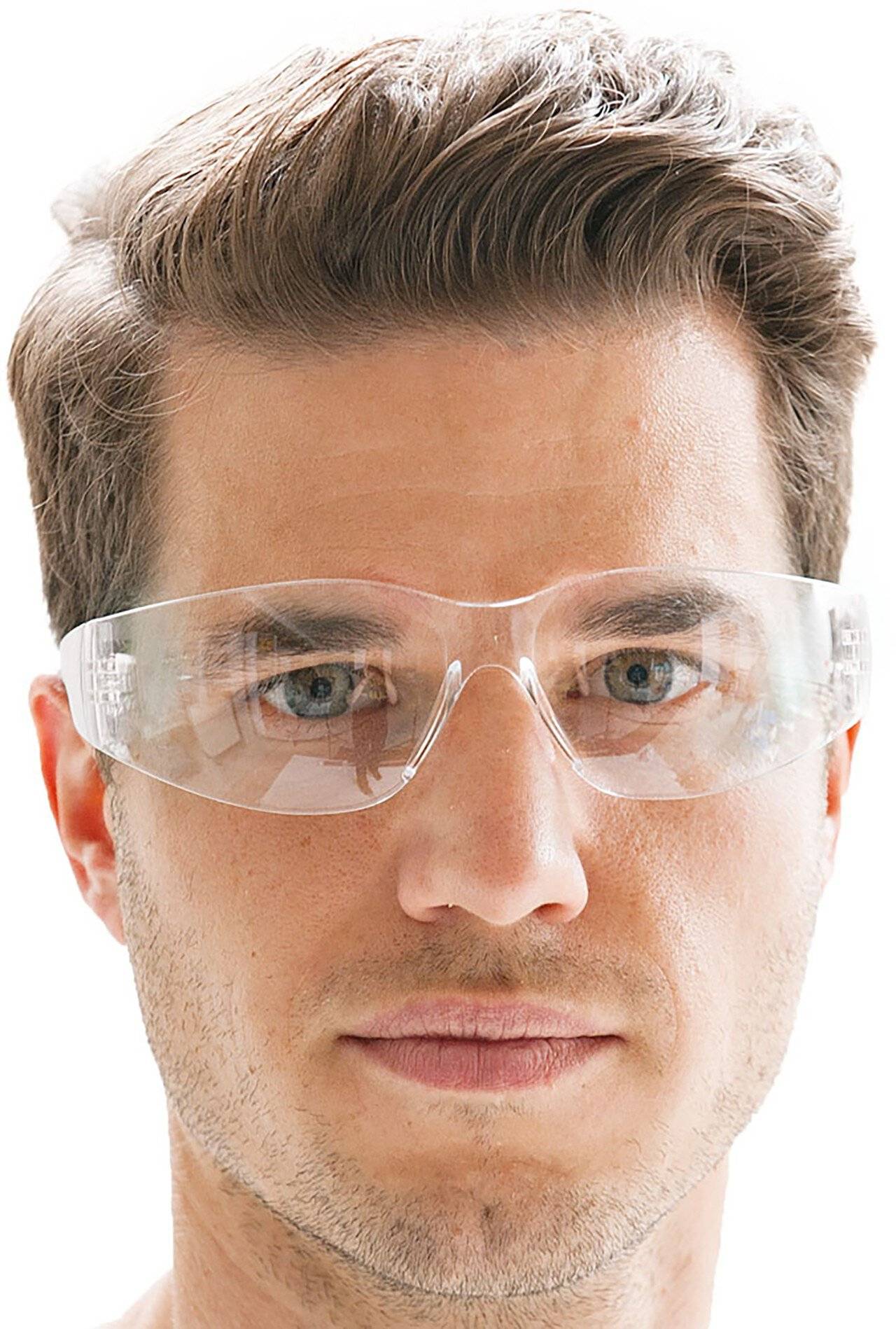 Nahaufnahme eines Mannes, der eine klare Schutzbrille trägt, geradeaus in die Kamera schaut, vor einem weißen Hintergrund.