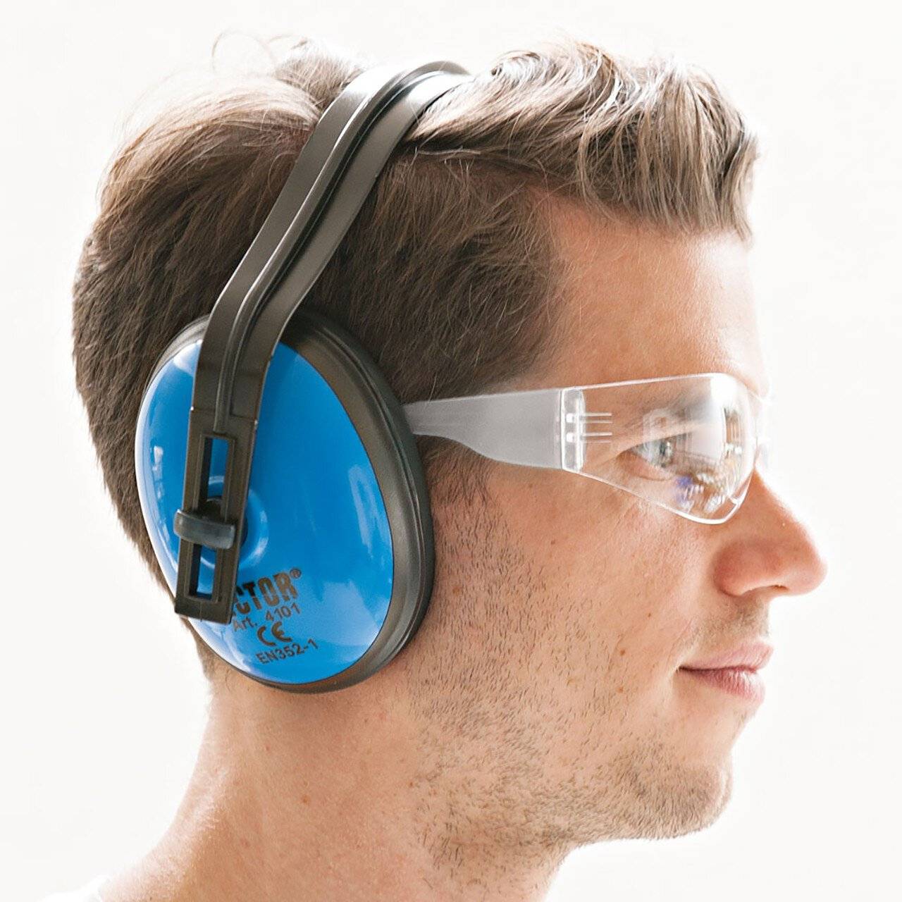 Profil eines Mannes, der blaue Ohrenschützer und klare Schutzbrille trägt, zeigt Gehör- und Augenschutz.