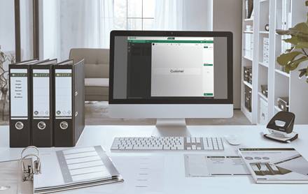 Moderner Büroschreibtisch mit iMac, auf dem ein Kundenverwaltungsbildschirm angezeigt wird, Ordner und Papierkram, Tastatur, Maus und Büromaterial.