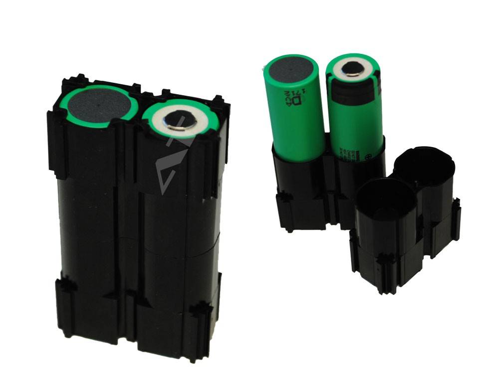 Zwei Ansichten eines schwarzen Batteriefachs mit zwei grünen zylindrischen Batterien auf weißem Hintergrund.
