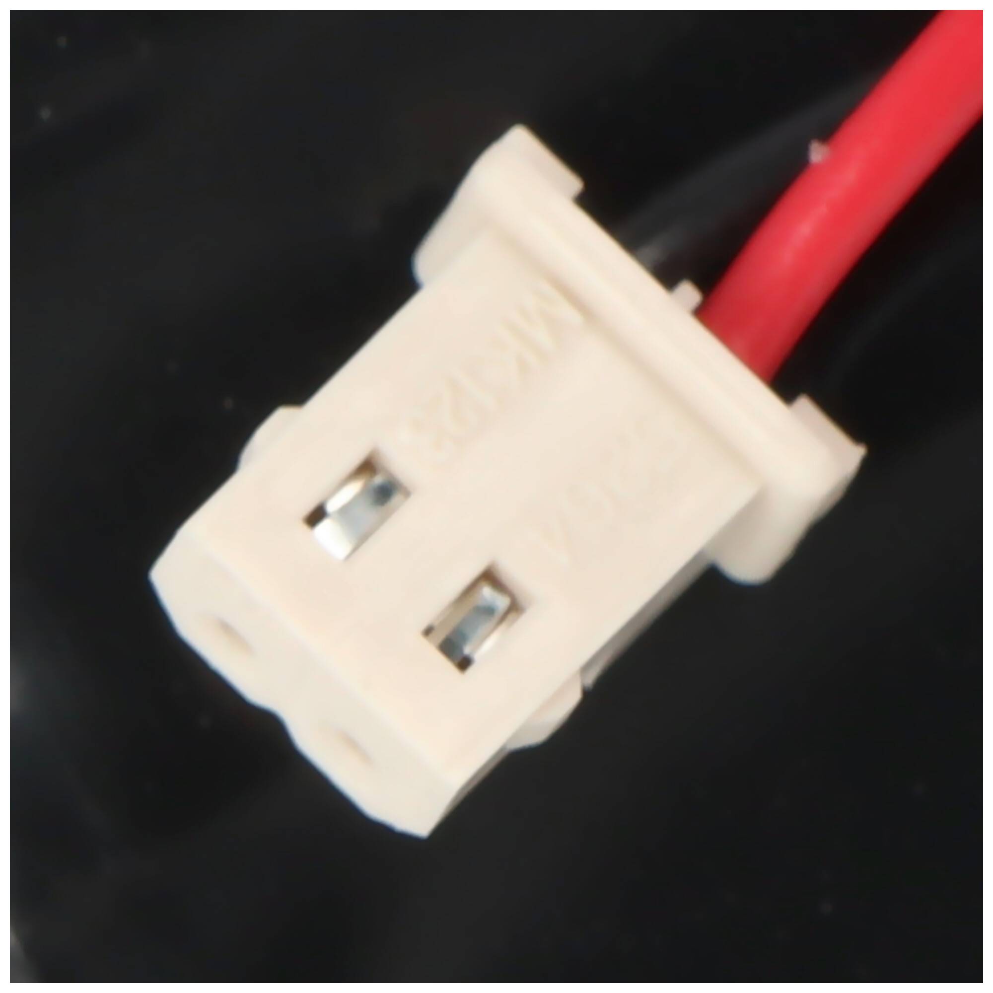 Nahaufnahme eines weißen zweipoligen Elektrosteckers, der an einem roten Draht auf dunklem Hintergrund angebracht ist.
