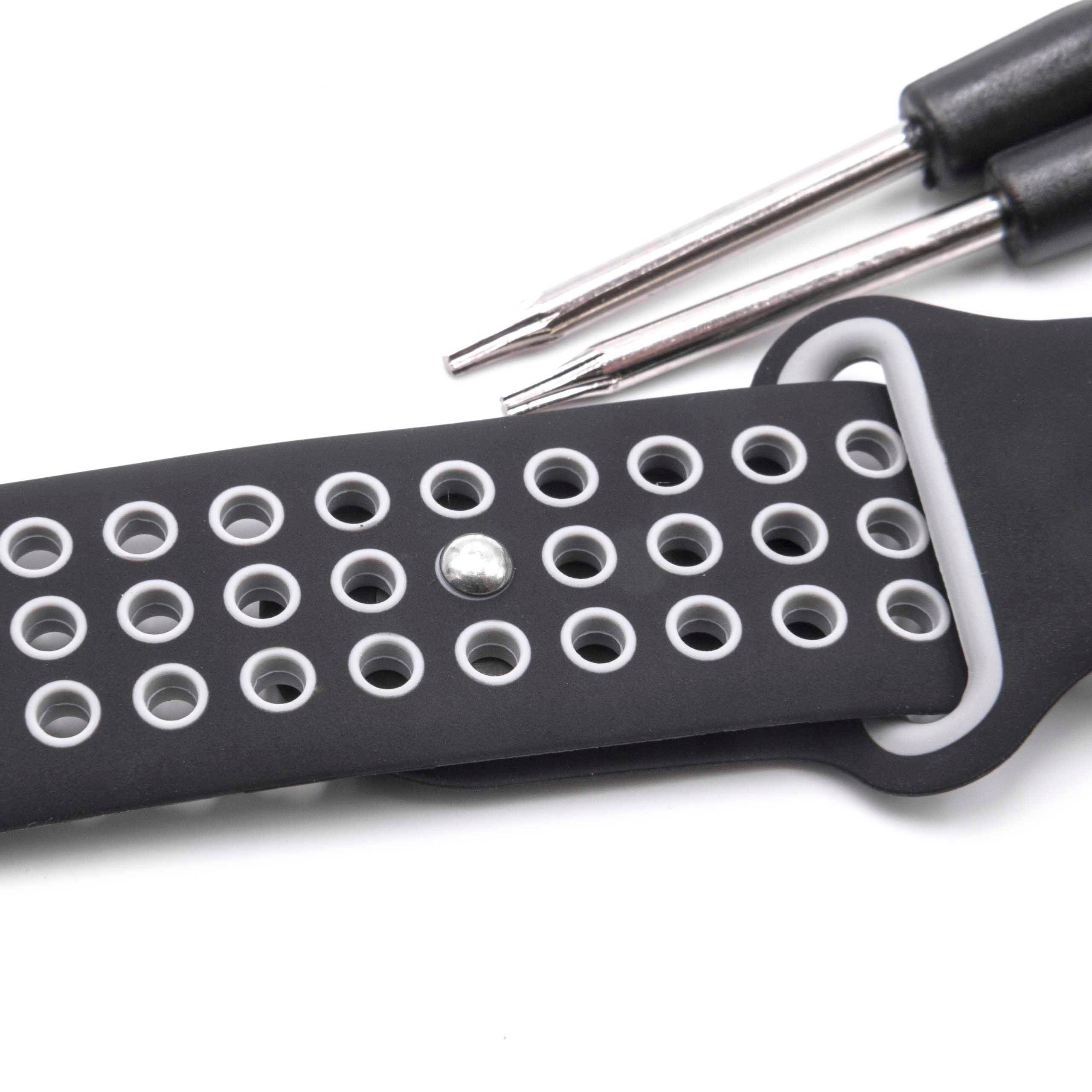 Ein schwarzes Uhrenarmband mit grauen Kanten, das mehrere kreisförmige Perforationen aufweist, zusammen mit einem kleinen Werkzeug mit zwei Metallzacken.