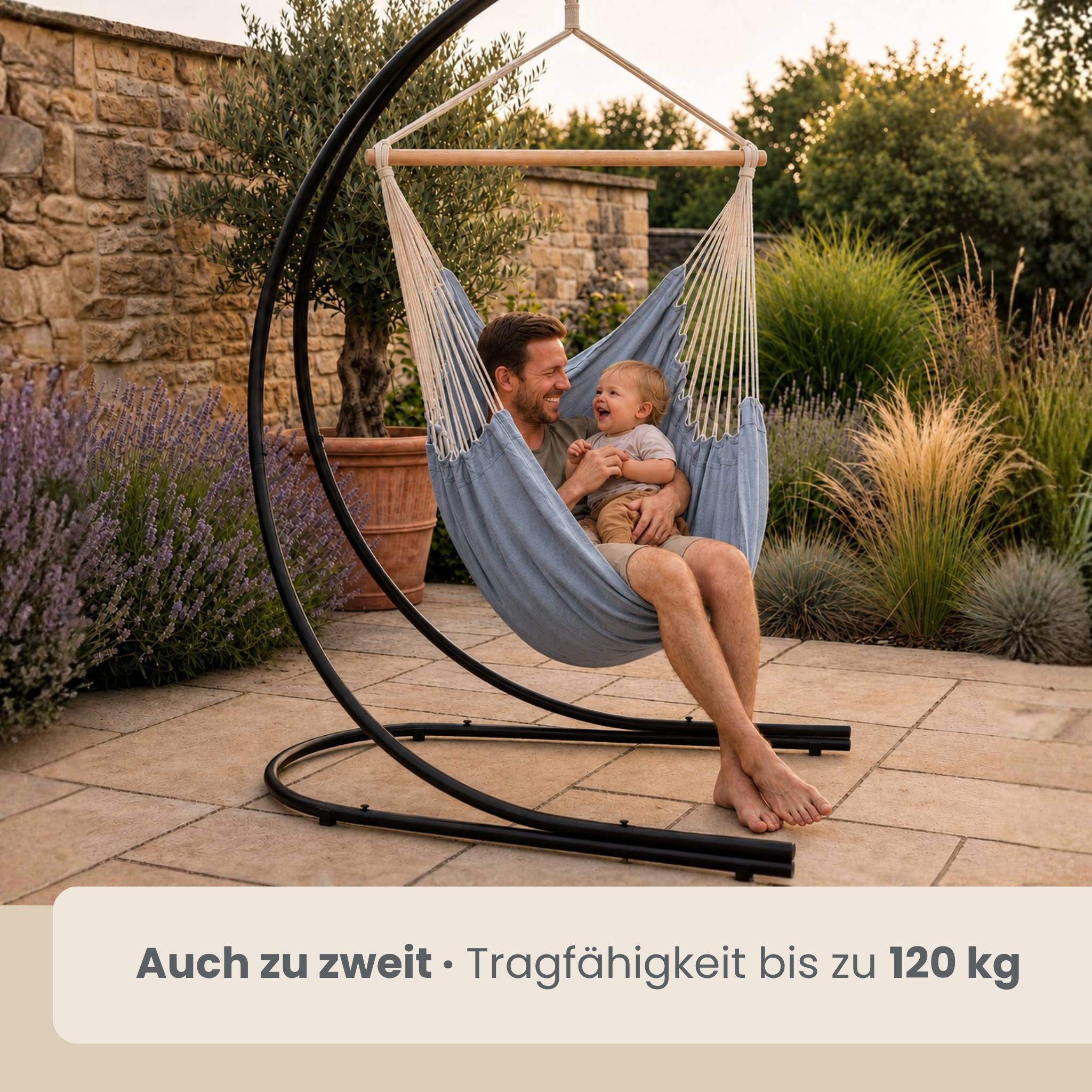 Vater und Baby lächelnd in einem hängenden Stuhl-Hängesessel im Freien; die Beschriftung sagt „Auch zu zweit · Tragfähigkeit bis zu 120 kg