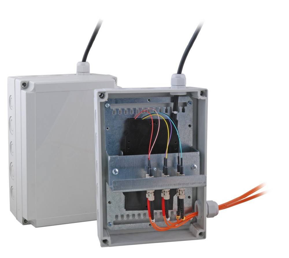 Elektrische Verteilerdose mit abgenommenem Deckel, die farbige Kabel und Anschlüsse im Inneren freilegt, verwendet zum Unterbringen von elektrischen Verbindungen.