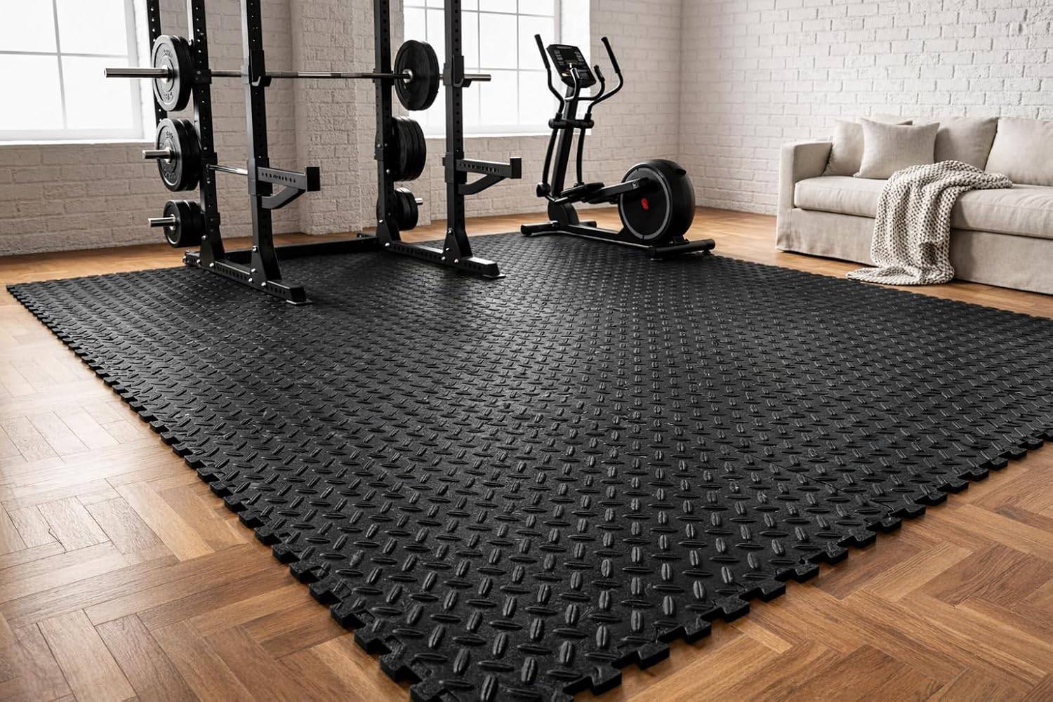 Heimfitnessraum mit großen schwarzen Gummibodenmatten, Gewichtregalen, einem Heimtrainer und einem Sofa im Hintergrund.
