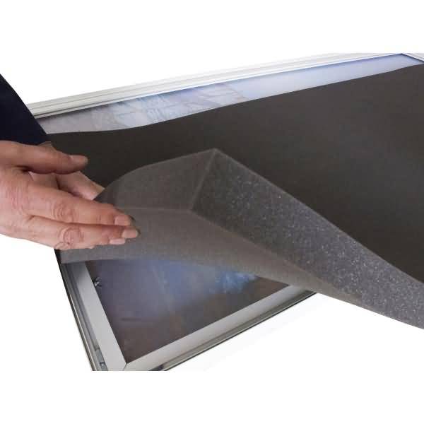 Hand, die eine schützende Schaumstofffolie von der Ecke eines Flachbildschirms oder Rahmenpaneels zurückzieht.