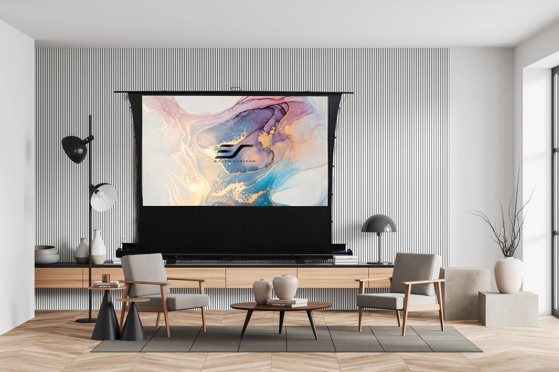 Modernes Wohnzimmer mit großer herunterfahrbarer Projektionsleinwand, die abstrakte farbenfrohe Kunstwerke zeigt, oberhalb einer niedrigen Kommode, flankiert von zwei Stühlen und einer Lampe.