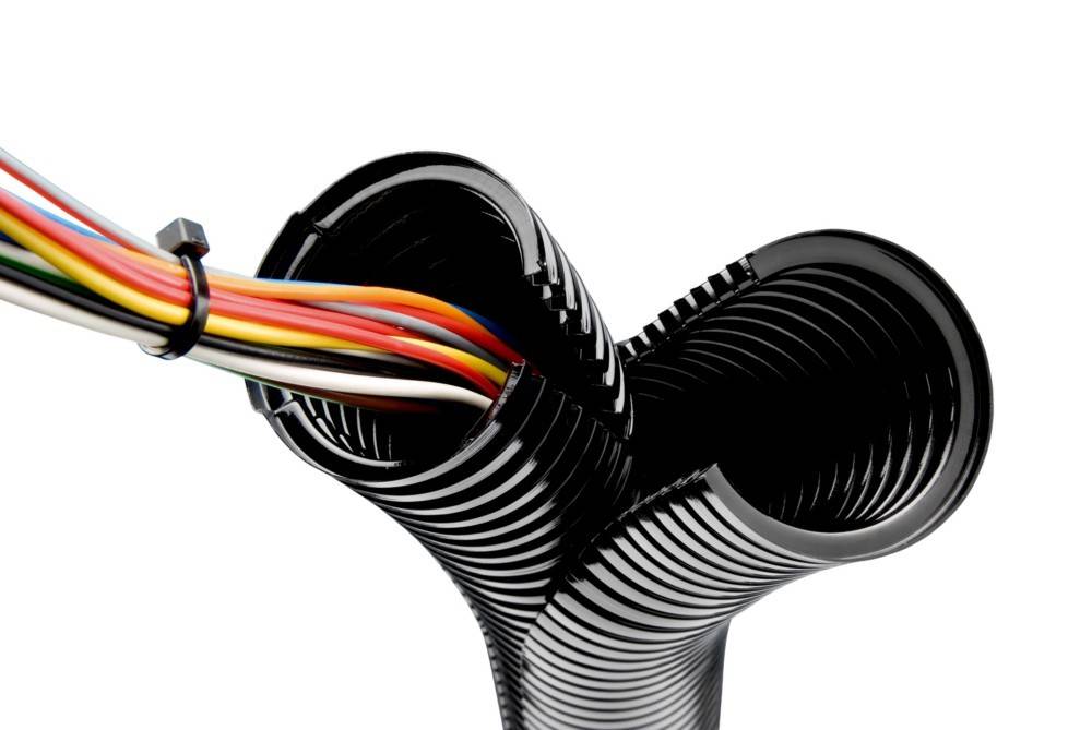 Eine Nahaufnahme eines schwarzen Spiralkabelhalters, teilweise geöffnet, der bunte Kabel im Inneren freilegt und Kabelmanagement oder -organisation andeutet.