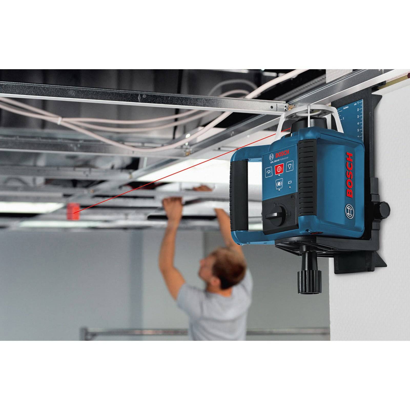 Eine Person nutzt einen an der Wand montierten Bosch-Laserlot, um Deckeninstallationen auszurichten. Der Laser projiziert eine rote Linie über den Raum.