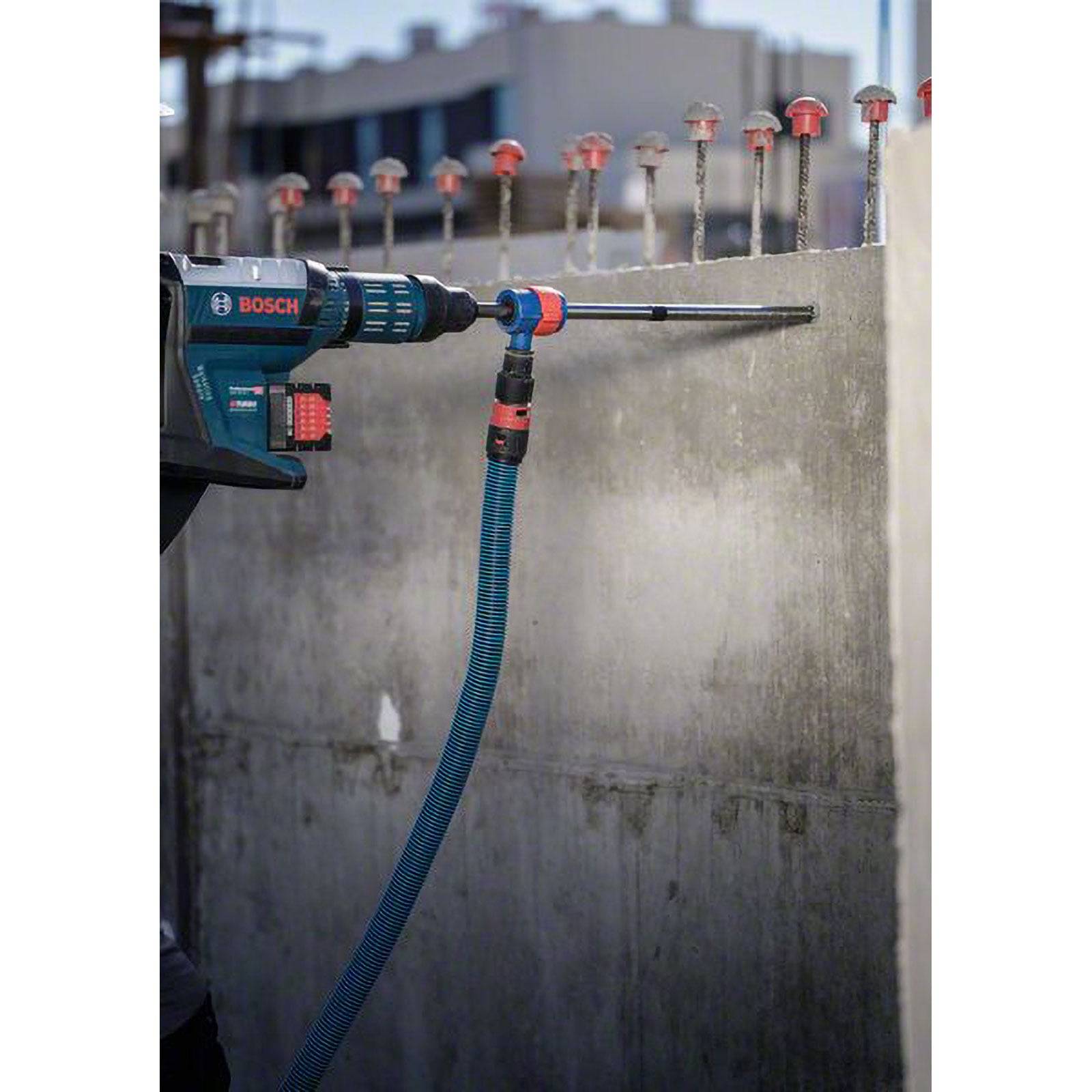 Ein Arbeiter benutzt ein Bosch-Werkzeug, um in eine Betonwand zu bohren und dabei Bauarbeiten zu demonstrieren, wobei Bewehrungsstahl oben sichtbar ist.