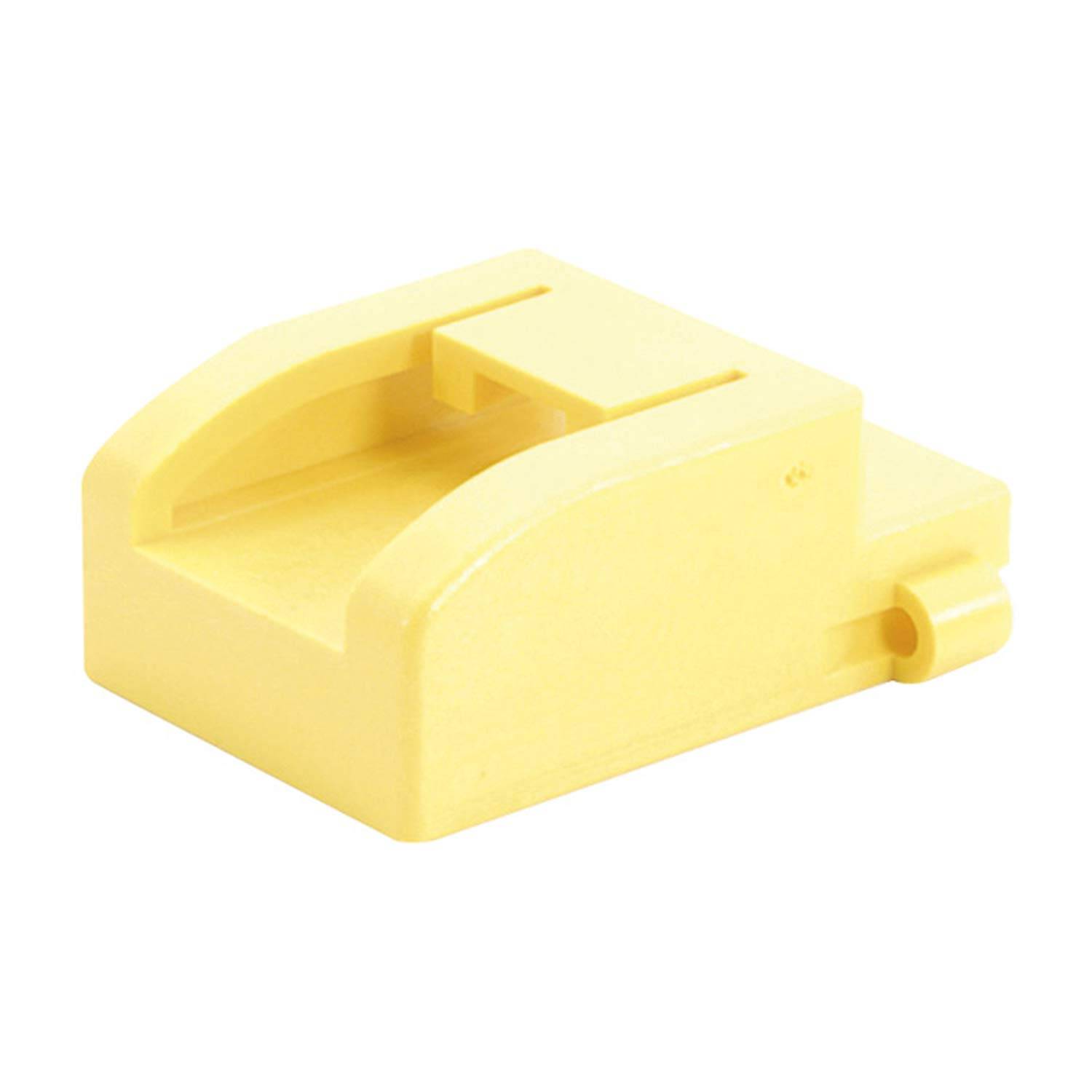 Ein gelber Kunststoffblock mit schräger Formgebung und einer kleinen Vorwölbung an der Seite, der einem Spielzeug oder Bauteil ähnelt.