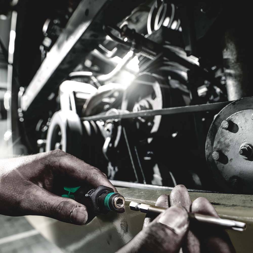 Eine Person, deren Hände einen Schraubenschlüssel benutzen, um an einer Maschine zu arbeiten, mit Fokus auf das Anziehen oder Lösen eines Bolzens in einer mechanischen Umgebung.