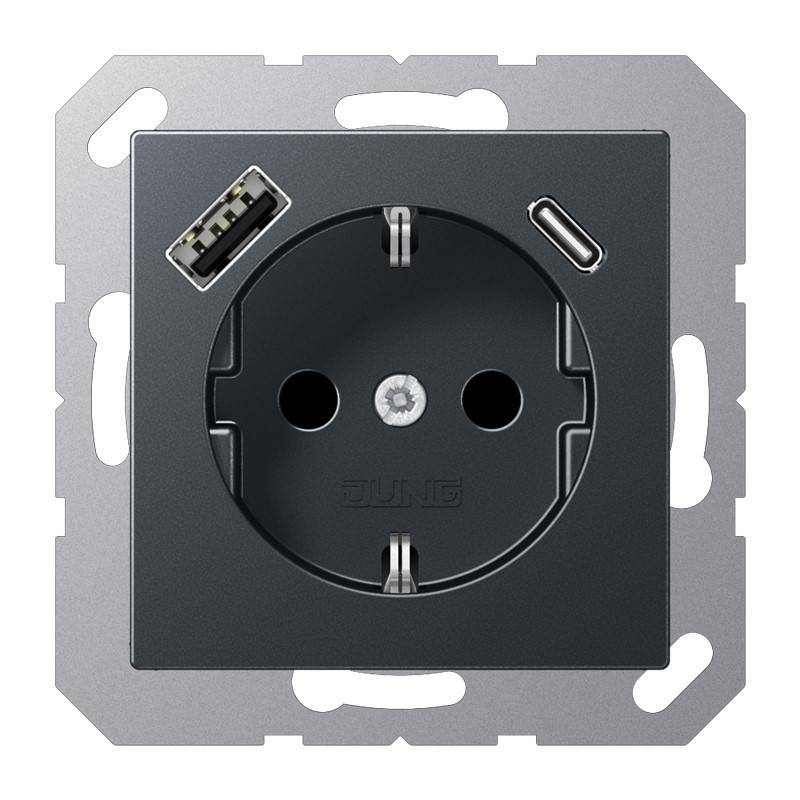 Wandmontierte schwarze Steckdose mit zwei runden Buchsen, einem USB-A-Anschluss und einem USB-C-Anschluss in einem Metallrahmen.