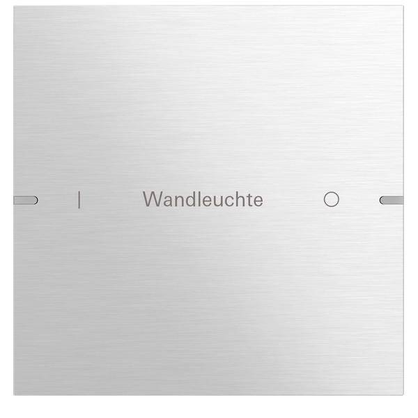 Ein gebürstetes Metallpanel mit dem Wort 'Wandleuchte' in grauer Schrift zentriert. Zwei kleine, vertikale Rillen sind auf beiden Seiten sichtbar.