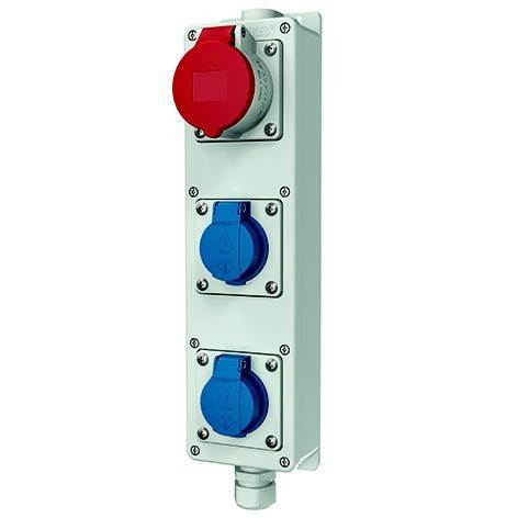 Industrielles Stromverteilerfeld mit einer roten Steckdose oben und zwei blauen Steckdosen darunter auf einem weißen Gehäuse.
