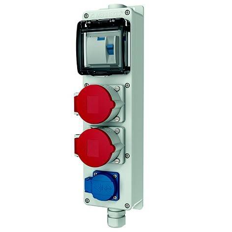 Wandmontierte Elektrosteckdose mit transparentem Deckel und drei runden Steckern: zwei rot und eine blau, für industrielle Stromverbindungen.