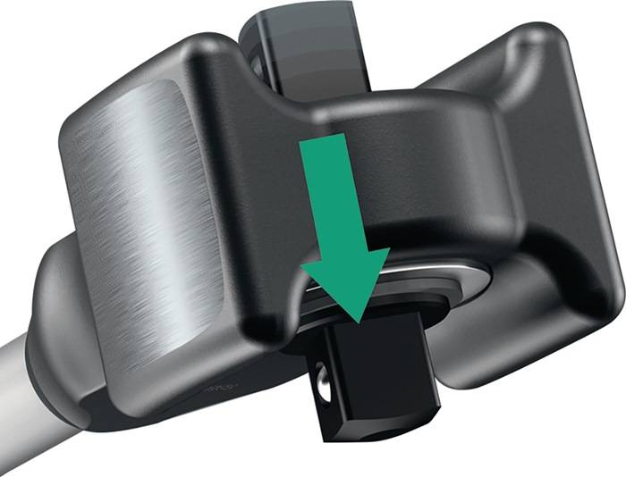 Nahaufnahme eines Metallwerkzeugs mit einem grünen Pfeil, der nach unten zeigt und die Richtung für das Einsetzen oder Entfernen einer Komponente angibt.