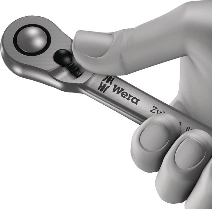 Eine Hand, die einen silbernen Wera-Ratschenschlüssel hält. Der Schraubenschlüssel verfügt über einen Klickmechanismus nahe dem Kopf und ist leicht nach oben gewinkelt.