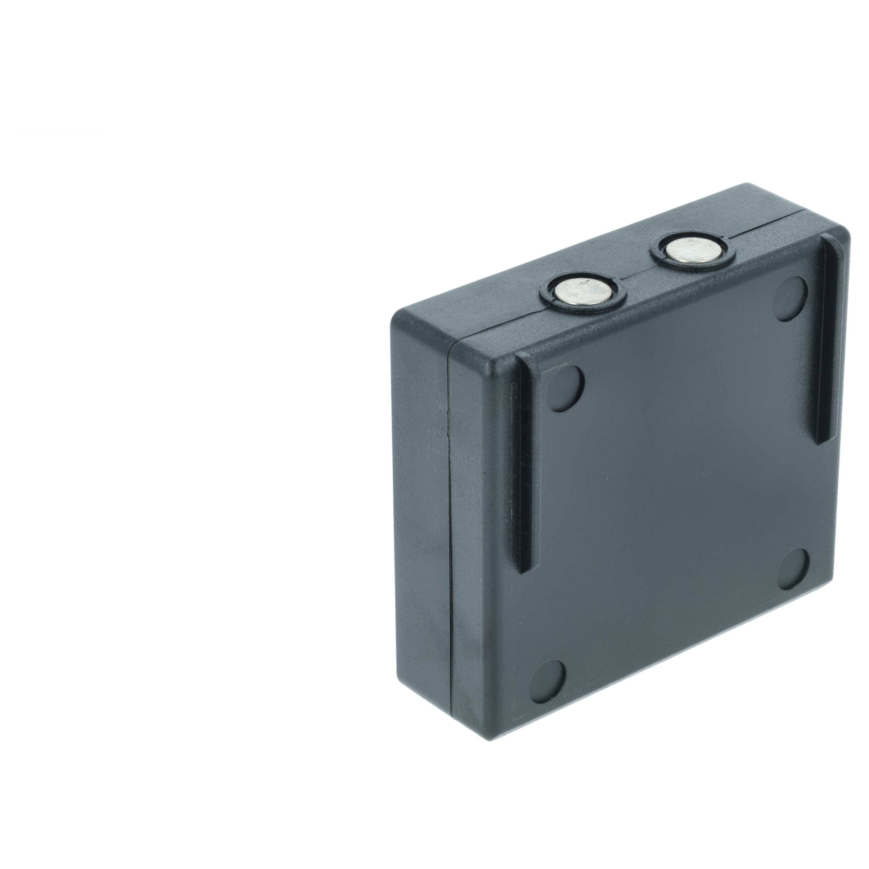 Eine rechteckige schwarze Kunststoffbox mit zwei kreisförmigen Metallverbindern auf der Oberseite, höchstwahrscheinlich eine elektronische Komponente oder ein Modul.
