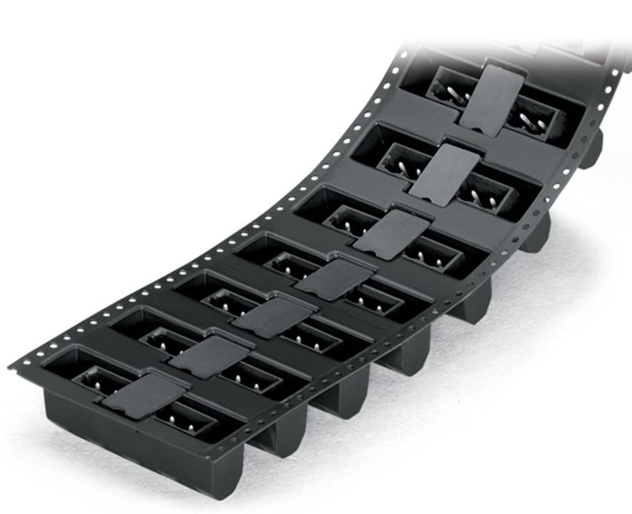 Eine schwarze Chipträgerfolie, die mehrere kleine elektronische Komponenten, wahrscheinlich IC-Chips, in einzelnen Fächern für Verpackung oder Transport aufnimmt.