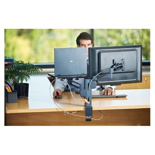 Mann, der an einem Schreibtisch hinter zwei Computermonitoren in einem Büro arbeitet und eine Tastatur sowie eine Maus benutzt.