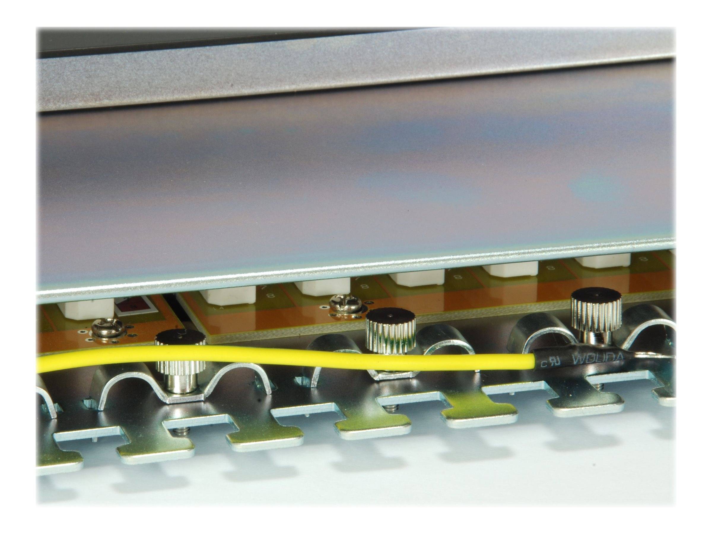 Nahaufnahme des Inneren eines elektronischen Geräts mit Schaltkomponenten, Steckverbindern und einem gelben Kabel unter einer Metallabdeckung.