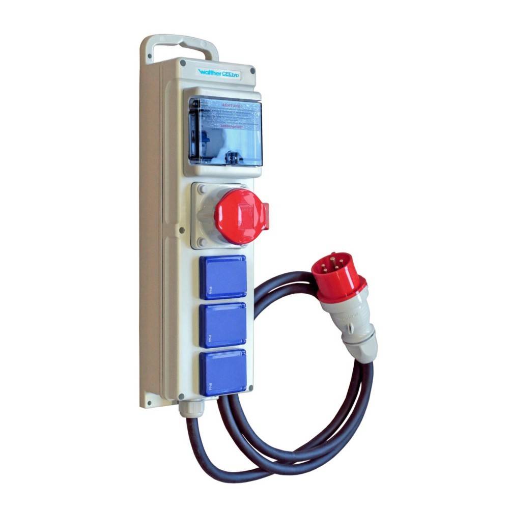 Ein vertikales, wetterfestes elektrisches Schaltpanel mit drei blauen Steckdosen, einem roten Drehschalter und einem roten industriellen Stecker, der durch ein Kabel verbunden ist.