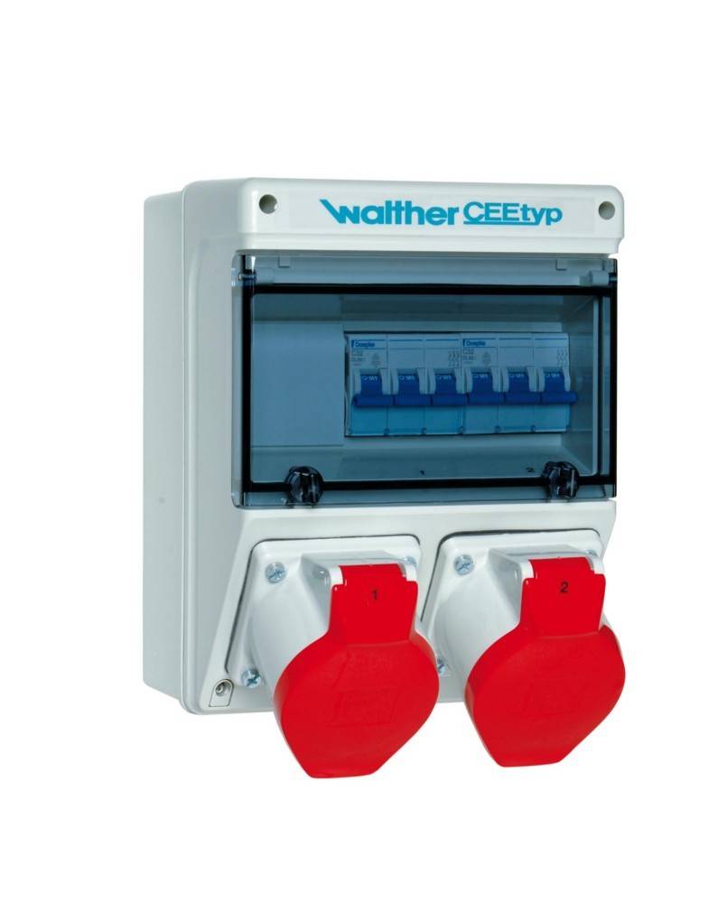 Eine elektrische Verteilerdose mit transparentem Deckel, der die Sicherungsautomaten im Inneren sichtbar macht, und zwei roten industriellen Stromsteckdosen darunter.