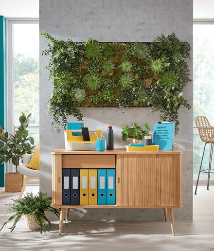 Modernes Büro mit einem Holzschrank, der Ordner und Materialien enthält, unter einem großen vertikalen Wandgarten mit üppig grünen Pflanzen.