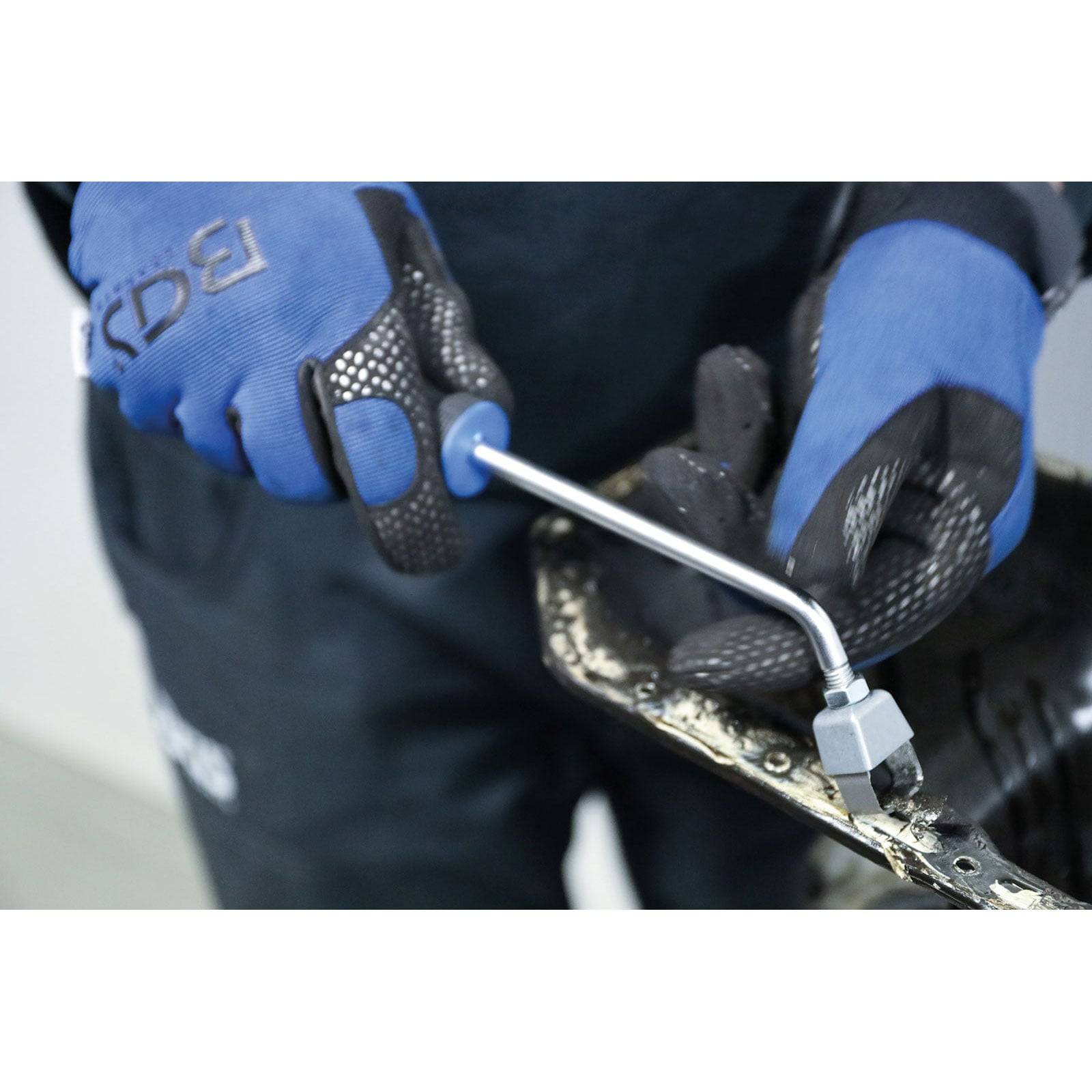 Eine Person mit blauen Handschuhen verwendet ein BGS-Werkzeug zum Entfernen von Schrauben von einem Motorbestandteil und demonstriert dabei Arbeiten zur Automobilwartung.