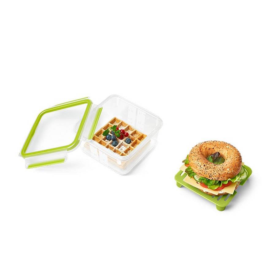 Wiederverwendbare Behälter mit grünem Deckel für Lebensmittel: einer offen mit Waffeln und Beeren, ein anderer geschlossen mit einem gestapelten Sandwich oder Bagel.