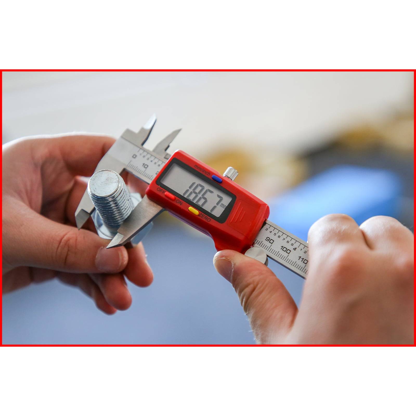 Eine Person misst einen Metallbolzen mit einer roten digitalen Schieblehre, die '18,57' auf dem Display zeigt und damit die Präzision der Messung unterstreicht.