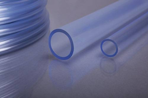 Nahaufnahme von transparenter blauer Plastikschlauch auf einer glatten Oberfläche, die Flexibilität und Transluzenz hervorhebt, mit einem nahe gelegenen aufgewickelten Schlauch.