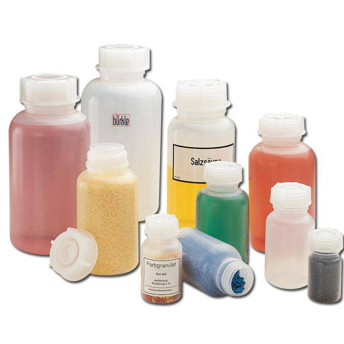 Verschiedene Laborcontainer, gefüllt mit farbigen Flüssigkeiten und Granulat in Rot, Weiß, Blau, Gelb und Schwarz, mit geöffneten Deckeln.