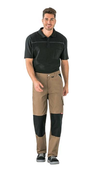 Ganzkörperaufnahme eines Mannes, der ein schwarzes Poloshirt und eine schwarz-beige Arbeitshose vor weißem Hintergrund trägt.
