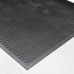 Eine strukturierte schwarze Gummimatte mit einem erhabenen Profilmuster auf einer weißen Oberfläche, die zum Verhindern von Ausrutschern konzipiert ist.