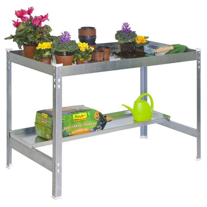 Metallischer Topftisch mit getopften Blumen, leeren Töpfen, Gartengeräten, einer Gießkanne und einem Sack universeller Blumenerde auf dem unteren Regal.
