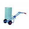 Ein blauer Handwagen mit schwarzen Rädern und einem roten Griff trägt eine große, aufrecht stehende zylindrische Trommel.