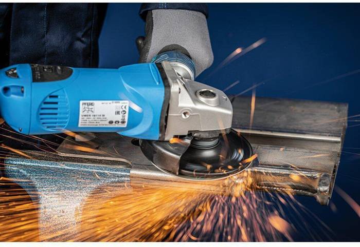 Eine Person verwendet einen blauen Winkelschleifer und emittiert Funken beim Schneiden von Metall, was Metallbearbeitung und die Funktionalität des Werkzeugs veranschaulicht.