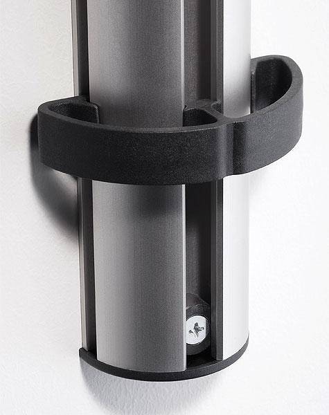Ein vertikales, metallisches Objekt mit einem gebogenen schwarzen Halter, der an einer Wand befestigt ist, möglicherweise Teil einer Montage- oder Stützstruktur.