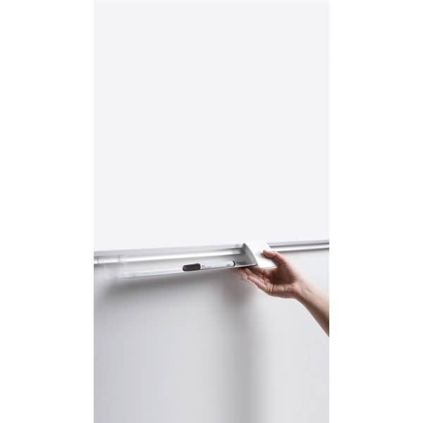 Hand, die eine Leuchtstoffröhre in eine wandmontierte Leuchte an einer schlichten weißen Wand einführt.