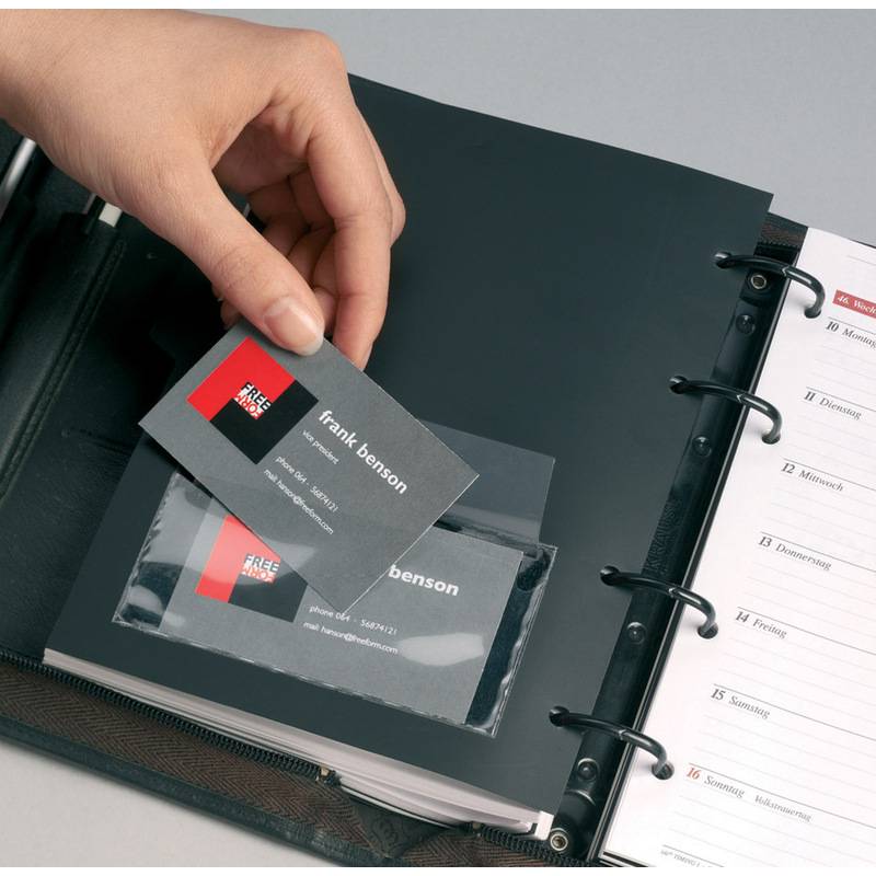 Eine Hand legt eine Visitenkarte in einen Halter innerhalb eines Organisers, der strukturierte Abschnitte und einen Wochenkalender mit sichtbaren Registerkarten zeigt.