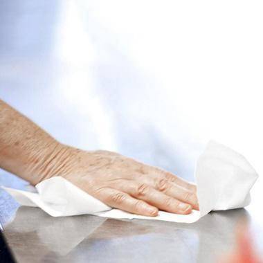 Hand beim Abwischen einer Edelstahloberfläche mit einem weißen Papiertuch
