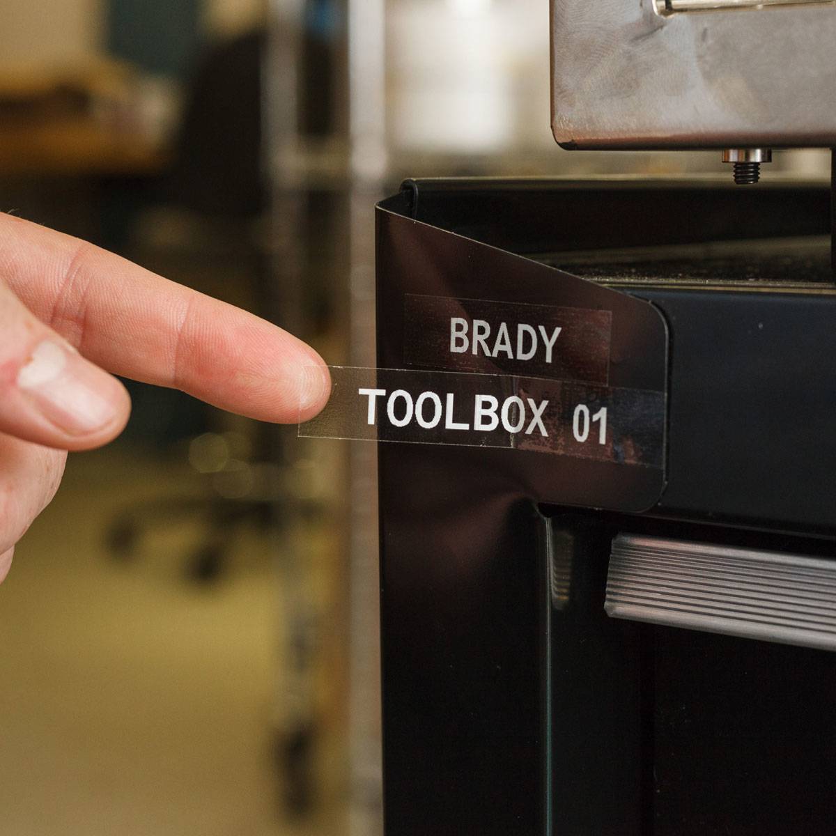 Eine Hand bringt ein durchsichtiges Etikett mit der Aufschrift „BRADY TOOLBOX 01